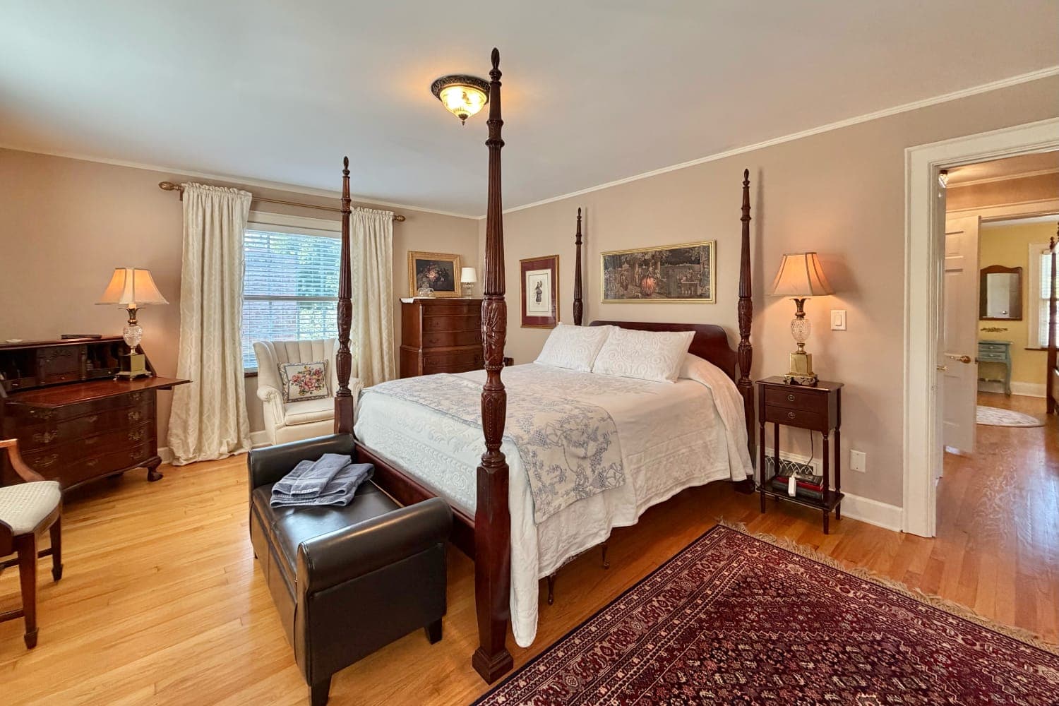 Cozy bedroom featuring a four-poster bed, wooden furniture, and warm lighting.