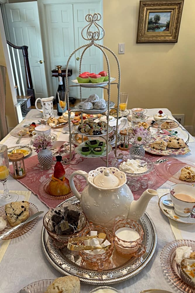 A beautifully arranged afternoon tea table with a tiered stand, teapot, and an assortment of pastries and scones.