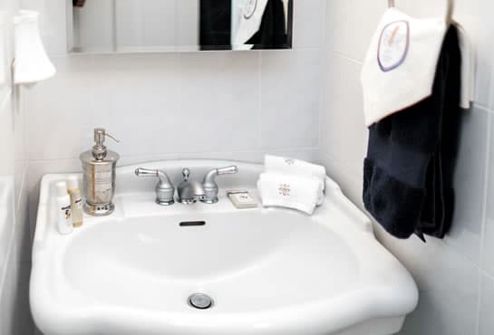 A modern bathroom sink with a mirror, soap dispenser, and neatly arranged towels.