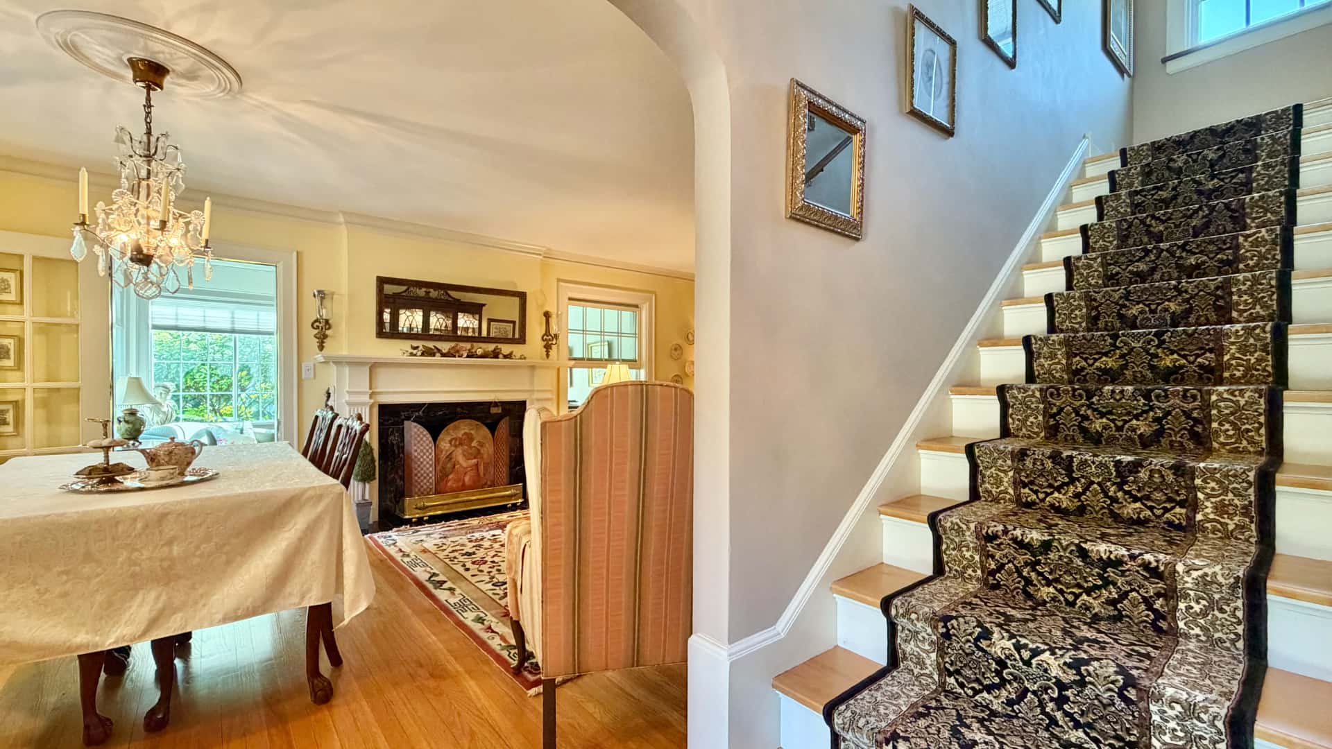 A cozy living space featuring a dining area, a fireplace, and a staircase with ornate carpeting.