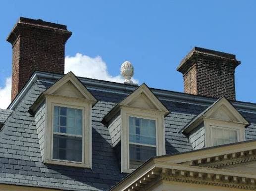 A decorative pineapple on the top of the roof of a house